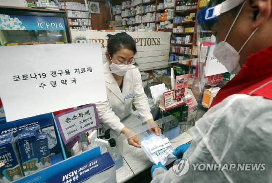 12일 오전 인천시 부평구 한 약국에서 열린 '코로나19 경구용(먹는) 치료제 투약 예행 연습'에서 부평구보건소 관계자가 치료제를 약국에서 수령해 환자에게 전달하는 연습을 하고 있다. <연합뉴스 제공>